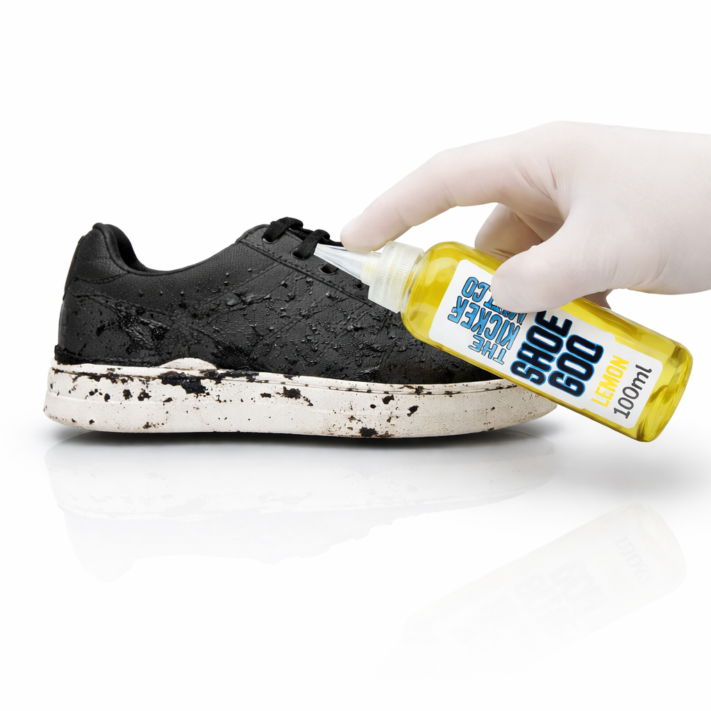 Person applying Shoe Goo to a black shoe with a white background